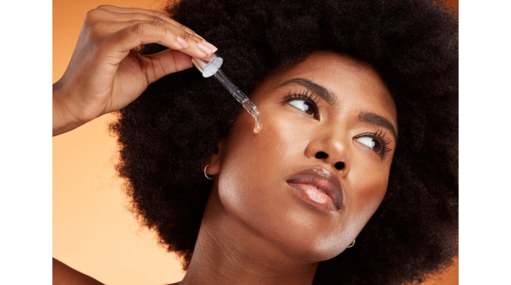 Stock photo of black woman using oil serum on her face